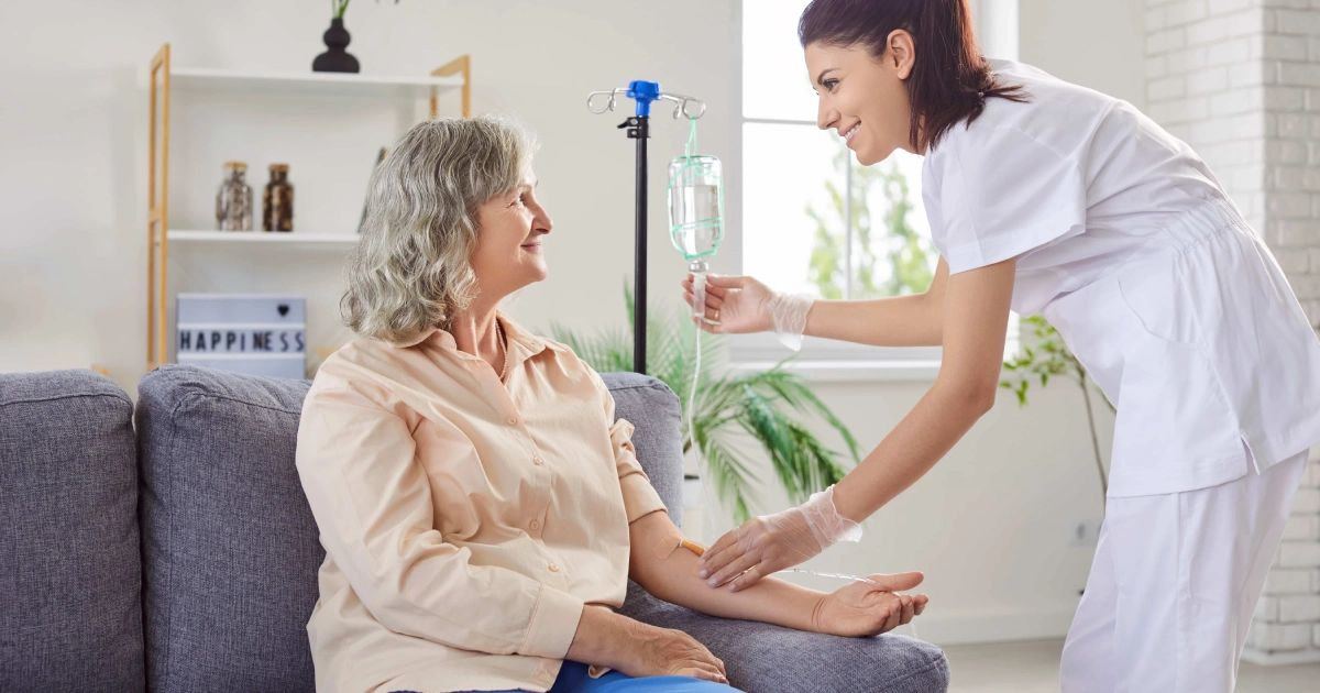 A young nurse gives Vitamin Injections in Grove City, Ohio, to a smiling older woman during a caring home visit.